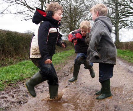 boys jumping in muddy puddles